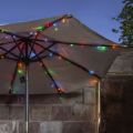 Lampki LED multikolor rozmieszczone na parasolu ogrodowym – wieczorna aranżacja świetlna z ciepłymi, kolorowymi punktami światła, dekoracja zewnętrzna IP44.