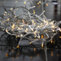 Lampki choinkowe LED o ciepłym świetle 3000K ułożone na mokrym podłożu, tworzące złocistą poświatę – oświetlenie zewnętrzne z transparentnym przewodem.