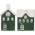 Zbliżenie na dwa zielone ceramiczne domki z białymi dachami i jasnymi oknami, pokazane na jednolitym tle. Prosta kompozycja podkreśla formę i kolor dekoracji.