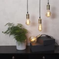 Wiszące dekoracyjne żarówki LED z filamentami w metalowych oprawkach nad komodą z rośliną doniczkową, aranżacja wnętrza w ciepłym świetle.