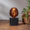 Żarówka LED E27 w bursztynowym szkle z widocznym spiralnym filamentem na czarnej podstawie. Dekoracyjne oświetlenie stołowe emitujące ciepłe światło do wnętrz.