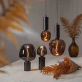 Dekoracyjne żarówki LED filament w przydymionym i bursztynowym szkle zawieszone oraz ustawione na czarnych lampach stołowych. Designerskie oświetlenie emitujące ciepłe światło dekoracyjne.