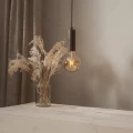 Żarówka LED E27 zawieszona w drewnianej oprawce nad stołem obok wazonu z suszonymi trawami. Ciepłe światło tworzy przytulną atmosferę wnętrza.