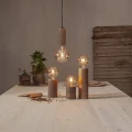 Dekoracyjne żarówki LED ustawione na drewnianych podstawach i zawieszone nad stołem. Ciepłe światło podkreśla naturalny, rustykalny charakter aranżacji.