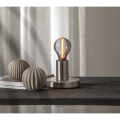 Dekoracyjna żarówka LED z dymionym szkłem zamontowana w nowoczesnej lampie stołowej ustawionej na ciemnym blacie obok dekoracyjnych elementów ceramicznych.