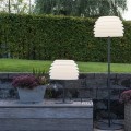 Lampa stołowa ogrodowa RHODOS z czarną smukłą podstawą i jasnym kloszem złożonym z poziomych warstw.