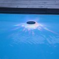 Dekoracyjna lampa solarna na powierzchni basenu, tworząca kolorowe refleksy świetlne rozchodzące się po wodzie po zmroku.