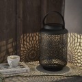 Dekoracyjny lampion LED ustawiony obok filiżanki na kamiennym blacie, rzucający ozdobne cienie w przytulnej aranżacji.