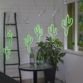 Neonowa dekoracja LED w kształcie kaktusa w kolorze zielonym, zawieszona na białej girlandzie świetlnej E27 w jasnym wnętrzu. Dekoracyjne światło tworzy nowoczesny, wyrazisty akcent aranżacyjny.