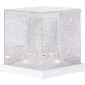 Dekoracyjna kostka LED z przezroczystego materiału z drobnymi połyskującymi elementami, pokazana na jednolitym tle.