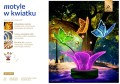 Motyle LED fotopunkt w formie dużego kwiatu z podświetlaną konstrukcją i kolorowymi skrzydłami, dekoracja parkowa do zdjęć ustawiona w zielonej przestrzeni miejskiej, przyciągająca uwagę intensywnymi barwami i efektem neonowego światła. ID 151025.