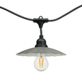 Girlanda świetlna CRETE z metalowym kloszem – zbliżenie pojedynczej oprawy E27 z czarnym, metalowym kloszem i żarówką LED A60 Soft Glow 2100K, widok na tle białym.