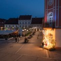 Wielkanocna dekoracja miejska LED w formie zająca z siedziskiem, instalacja świetlna ustawiona na rynku wśród zabudowy miejskiej i latarni.