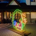 Iluminacja wielkanocna Bramka Wiosna 3D LED z zieloną konstrukcją, kolorowymi pisankami i kwiatami, dekoracja plenerowa do miast i obiektów komercyjnych, widok boczny.