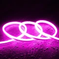 Różowy wąż LED NEON w elastycznym, falistym układzie, emitujący delikatne światło na ciemnym tle.