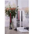 Zestaw czerwonej i czarnych świec LED w wysokich świecznikach na stole przy wazonie z kwiatami.