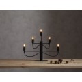 Świecznik elektryczny w kolorze czarnym z pięcioma ramionami i żarówkami LED, ustawiony na stole obok lnianej tkaniny i gałązek.