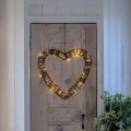 Podświetlane serce LED wykonane ze sztucznego ratanu, zawieszone na drzwiach z jasnego naturalnego drewna, emitujące ciepłe światło.