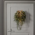 Wianek świąteczny LED z jutową kokardą i długimi gałązkami, zawieszony na białych drzwiach – elegancka dekoracja w naturalnym stylu.