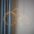 Kompozycja wiszących wianków LED o delikatnej formie, wprowadzająca ciepły, świąteczny nastrój na tle neutralnej, przytulnej aranżacji wnętrza.