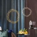 Dwie wiszące dekoracje LED: większy okrąg w kolorze złota i mniejszy w kolorze chromu, oba z drobnymi punktami światła, zawieszone na tle ciemnej zasłony w eleganckim wnętrzu.