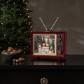 Świąteczna aranżacja z podświetlanym telewizorem retro LED w czerwonej obudowie, w którym rodzina bałwanków stoi wśród choinek i „śniegu”, ustawionym na komodzie obok miski z orzechami i choinki w tle.