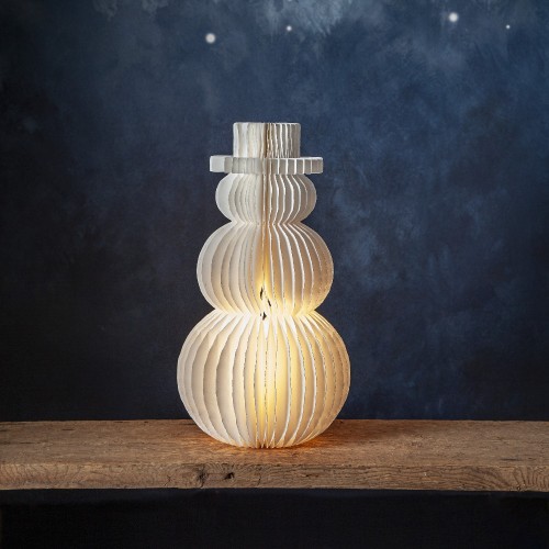 Dekoracja LED w kształcie bałwanka z papieru, delikatnie świecąca od środka, ustawiona na drewnianej półce; subtelne światło tworzy ciepły, nastrojowy klimat zimowej aranżacji.
