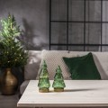 Dwie szklane choinki LED z zielonego, przezroczystego szkła, ustawione na jasnym stole. Ciepłe światło, w tle sofa i poduszki. Harmonijna, przytulna dekoracja do domu.