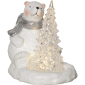 Figurka białego misia z brokatowym wykończeniem i szalikiem, obok przezroczystej choinki z ciepłym światłem LED, pokazana na jednolitym tle. Delikatne światło podkreśla zimowy charakter dekoracji.