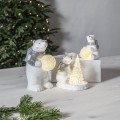 Trzy dekoracyjne figurki białych misiów z podświetleniem LED, dwa z nich trzymają świecące śnieżne kule, a jeden siedzi przy podświetlanej choince. Aranżacja na jasnym blacie w spokojnym, świątecznym stylu.
