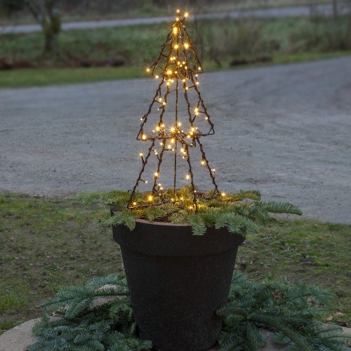 Mała choinka świetlna LED na metalowym stelażu, ustawiona w czarnej donicy z gałązkami igliwia. Ciepłe światło tworzy delikatną, zimową dekorację na zewnątrz.