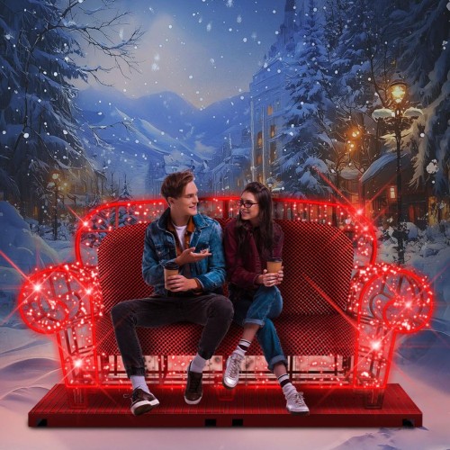 Walentynkowa sofa LED 3D w czerwonym kolorze, ustawiona w zimowej scenerii miejskiej. Para siedzi na podświetlanej sofie z dekoracyjnymi sercami LED, tworząc romantyczny fotopunkt plenerowy.