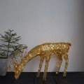 Dekoracja świetlna LED w kształcie złotego jelenia ustawiona na ciemnym podłożu; ciepłe światło podkreśla błyszczące detale formy, jasna ściana w tle.