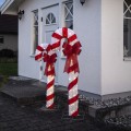 Dwie świąteczne dekoracje LED w kształcie lasek cukrowych, ustawione obok wejścia do domu. Ciepłe światło LED podkreśla czerwone pasy i kokardy, tworząc klasyczną bożonarodzeniową aranżację.