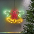 Dekoracja neon LED przedstawiająca dzwonki z kokardą, zawieszona na ścianie obok choinki. Ciepłe, kolorowe światło tworzy wyraźny kontur i harmonijny, świąteczny nastrój.