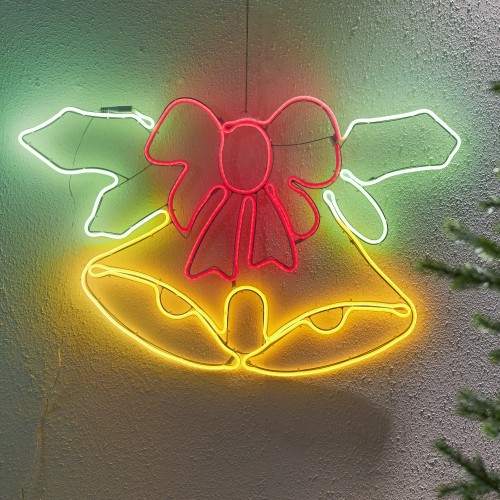 Dekoracja świetlna neon LED w kształcie dzwonków z kokardą, zamontowana na ścianie. Żółte, czerwone i zielone światło tworzy wyraźny kontur motywu i przytulny, świąteczny efekt.