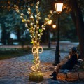 Dekoracja świetlna „Bazie w Bukiecie 3D” – wolnostojący bukiet z gałązek bazi z ciepłym światłem LED, ustawiony na alejce parkowej obok ławki i latarni, tworzący nastrojowy, przytulny klimat wieczorem.