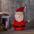 Dekoracja świetlna LED w kształcie Świętego Mikołaja z czerwoną czapką i zielonymi rękawiczkami, ustawiona we wnętrzu przy ścianie. Ciepłe światło równomiernie podświetla postać i tworzy świąteczny klimat.