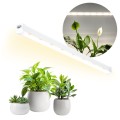 Lampa LED GROWLY 15W zamontowana nad roślinami doniczkowymi, emitująca światło wspierające wzrost liści i kwitnienie w warunkach domowych.