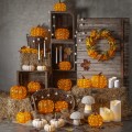 Jesienna kompozycja z dekoracjami LED w kształcie dyni w kolorze pomarańczowym świecami i naturalnymi dodatkami ustawiona we wnętrzu rustykalnym ciepłe światło podkreśla faktury i tworzy przytulny klimat.