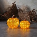 Dwie dekoracje LED w kształcie dyni w kolorze pomarańczowym w różnych rozmiarach ustawione obok siebie na podłodze w rustykalnym wnętrzu ciepłe światło tworzy spójną i przytulną aranżację jesienną.