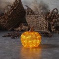 Dekoracja LED w kształcie dyni w kolorze pomarańczowym ustawiona na podłodze w rustykalnym wnętrzu ciepłe światło delikatnie podkreśla strukturę dekoracji i tworzy przytulny jesienny klimat.
