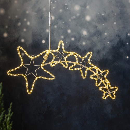 Świąteczna dekoracja LED w kształcie komety z gwiazdami zawieszona na przewodzie na tle zimowej aranżacji delikatne światło podkreśla kontur dekoracji i tworzy nastrojowy świąteczny klimat.