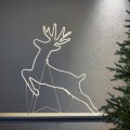 Świąteczna aranżacja z dekoracją LED w kształcie renifera ustawioną we wnętrzu na tle jasnej ściany subtelne światło podkreśla linię sylwetki dekoracji.