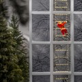 Świąteczna dekoracja LED z Mikołajem wspinającym się po świetlnej drabinie zawieszonej w oknie budynku emitująca ciepłe białe światło.