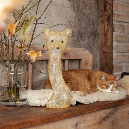 Świąteczna aranżacja z lisem LED ustawionym na drewnianej ławie obok szklanego naczynia z gałązkami, w tle śpiący kot i naturalne elementy wnętrza.