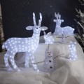 Świecące figurki LED przedstawiające renifera, króliki i bałwanki ustawione na jasnej dekoracyjnej powierzchni, z iglastymi gałęziami i ciemnym tłem imitującym nocną scenerię.