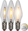 Trzy zapalone żarówki LED filament w kształcie świeczek ustawione obok siebie. Widoczne różne poziomy jasności światła oraz metalowe gwinty E10. Obok symbol „3-Step Dimming”, tło białe.