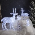 Zimowa dekoracja LED przedstawiająca białe figury reniferów, zająców i bałwanków ustawione na śniegu. W tle drzewa oraz ośnieżone gałęzie.