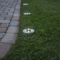 Solarne oprawy ogrodowe LED montowane w gruncie z okrągłą obudową i zintegrowanymi diodami, emitujące światło jako oświetlenie ścieżki i podjazdu.